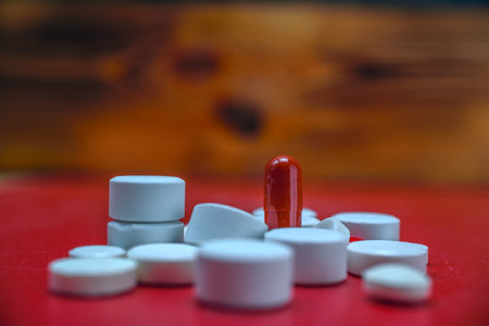 Close up of red and white pills on wooden background. Focus on foregroundの写真素材
