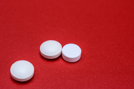 White pills on red background. Focus on foreground, shallow DOF.の写真素材