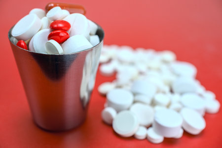 Pills in a metal cup on a red background. Focus on foreground.の写真素材