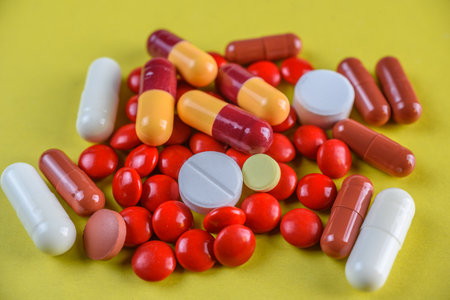 Pills and capsules on yellow background. Focus on foreground, soft bokeh.の写真素材