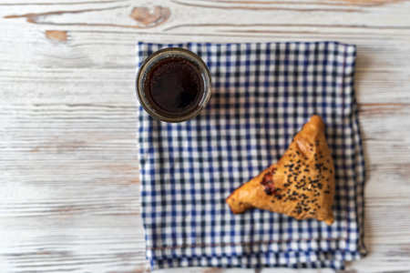 Samsa with meat on a napkin in a cage, next to a glass of juice. Photographed from above close-up.の写真素材