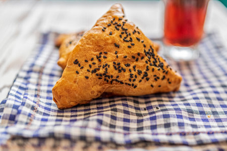 Samsa with meat on a napkin in a cage, next to a glass of juice. Photographed from above close-up.