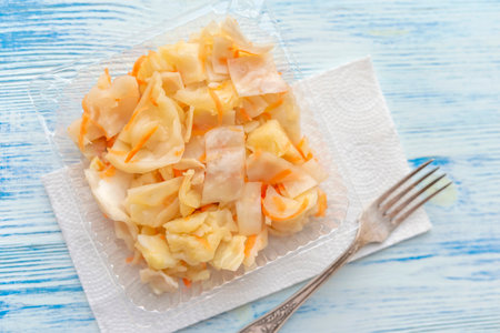 Sauerkraut salad in a plastic container on a wooden background.の写真素材