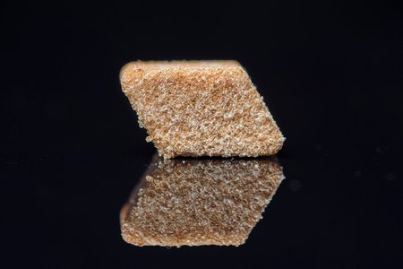 A piece of refined sugar on a black background. Photographed close-up.の写真素材
