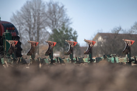 Red tractor plowing a field with flying birds in the background, showcasing agricultural activity...
