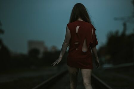 girl in torn red clothes on the railroad dirt on the body dark tones violence themeの写真素材