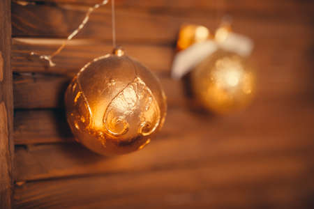 Image of two gold New Year baubles hanging on wooden door brown grungy wall decorated cozy home festive decorの写真素材
