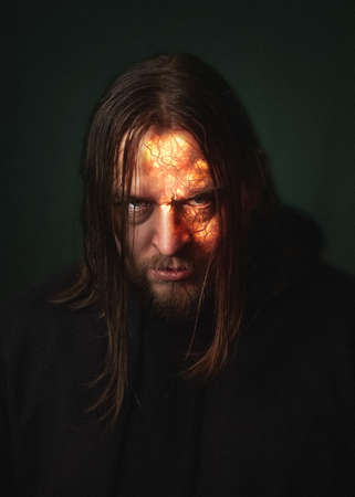 A demon man with a burning face in a fire sparks and smoke on dark green background Halloween devil horrorの写真素材