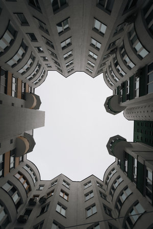 bottom view of gray clouds in sky between old brick house in the big city in winter evening...