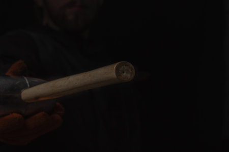 The hand holds a rubber mallet with a wooden handle lose up Isolated on a black backgroundの写真素材