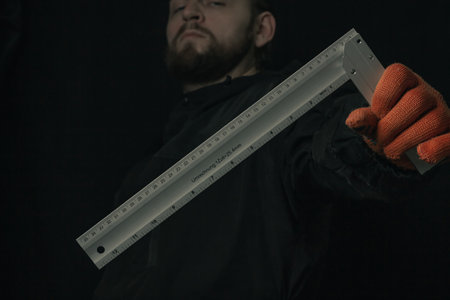 joiner hand holding yellow water level and angle ruler device isolated on black background close-up...