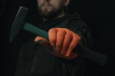 A man hand holds a hammer isolated on a black background