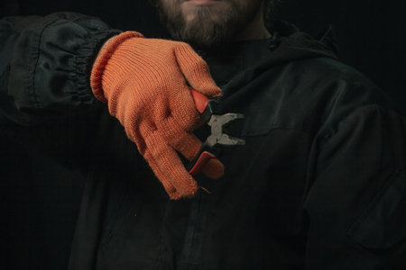 man's hand holding a black and red wire cutter plier open ready to cut form