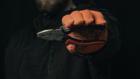 man's hand holding a black and red wire cutter plier open ready to cut formの写真素材