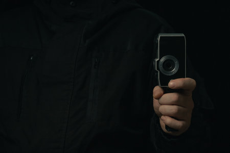 Vintage movie camera in man hand isolated on a blackbackgroundの写真素材