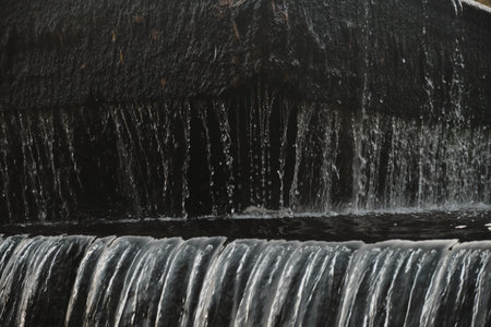 A waterfall flowing at park Wall of water A beautiful view of the falling water cascade city fountain close-up pouringの写真素材