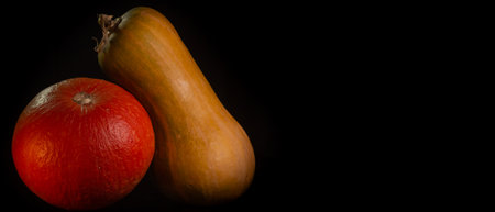 Yellow-orange pumpkins on a black background the concept of Halloween and the autumn harvest of...