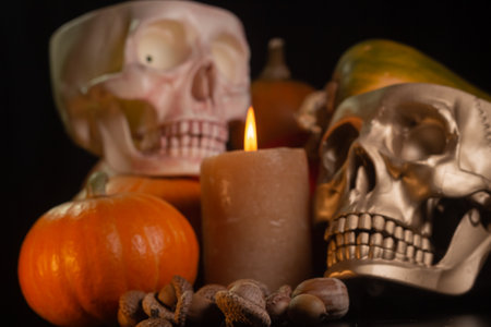 Yellow-orange pumpkins with candles and skulls on a black background the concept of Halloween and the autumn harvest of pumpkin close-up copyspace from aboveの写真素材