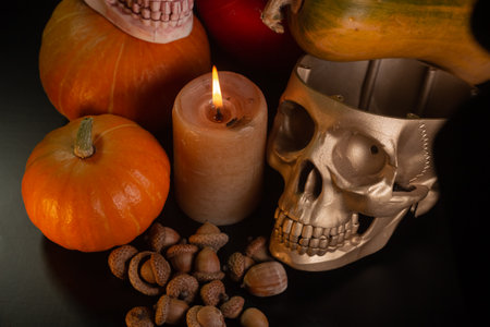 Yellow-orange pumpkins with candles and skulls on a black background the concept of Halloween and...