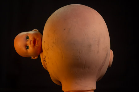 Damaged Dirty Doll head on black background isolatedの写真素材