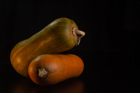 Yellow-orange pumpkins on a black background the concept of Halloween and the autumn harvest of pumpkin close-up copyspace from aboveの写真素材