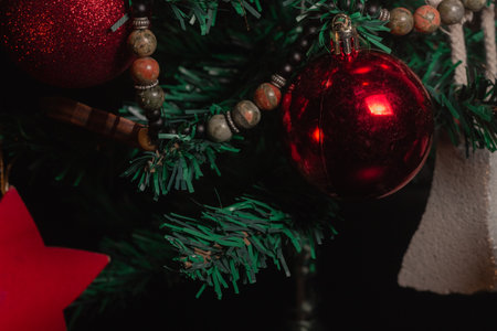 Red Christmas ball on a Christmas tree with a garland on the black backgroundの写真素材