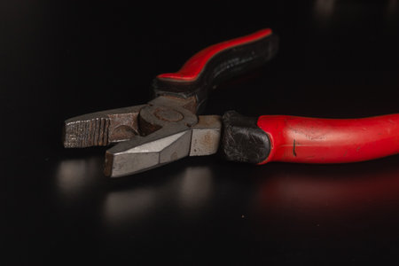 Pliers Open metal nippers with a red and green handle isolated on black background