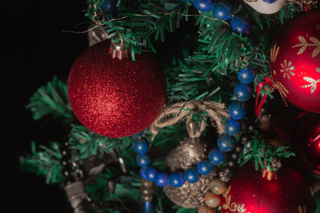 Red Christmas ball on a Christmas tree with a garland on the black backgroundの写真素材