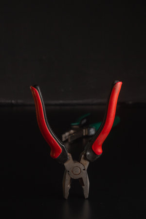 Pliers Open metal nippers with a red and green handle isolated on black backgroundの写真素材