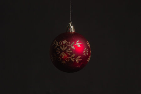 Red Christmas ball on a Christmas tree with a garland on the black backgroundの写真素材