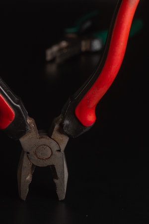 Pliers Open metal nippers with a red and green handle isolated on black background