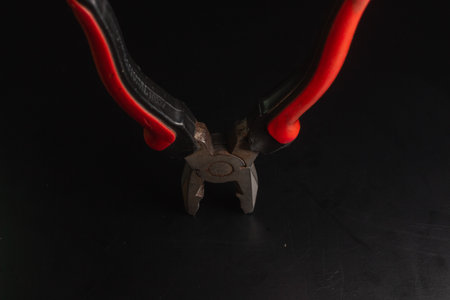 Pliers Open metal nippers with a red and green handle isolated on black background