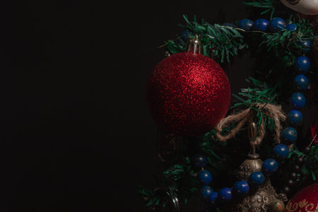 Red Christmas ball on a Christmas tree with a garland on the black backgroundの写真素材