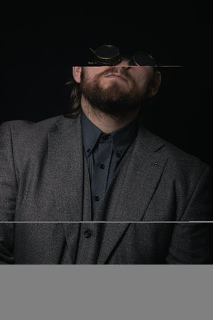 charismatic man in a classic suit and steampunk goggles on a black background stylish Portrait
