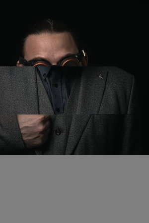 charismatic man in a classic suit and steampunk goggles on a black background stylish Portraitの写真素材