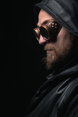 A man in a hood, wearing vintage steampunk goggles looking at the camera close-up