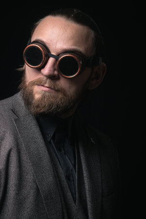 charismatic man in a classic suit and steampunk goggles on a black background stylish Portraitの写真素材
