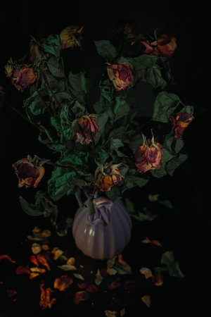 Macro close up multicolored orange dried rose bloom bouquet in ceramic retro vase Black backgroundの写真素材