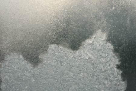 Beautiful ice pattern and sunlight closeup on window glass early in the morning natural winter...