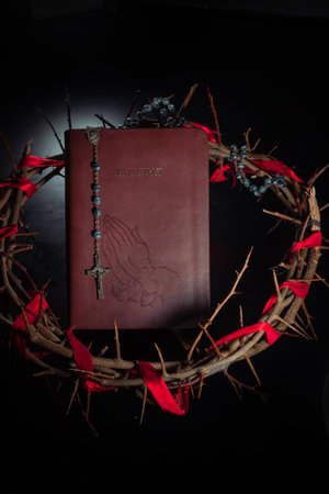Rosary beads and crucifix cross on holy bible background with crown of thornsの写真素材