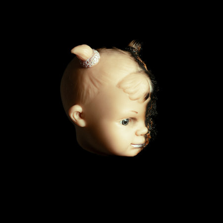 scary Isolated spooky possessed baby girl doll head creepy burnt face with gray eye on black background Close up macroの写真素材