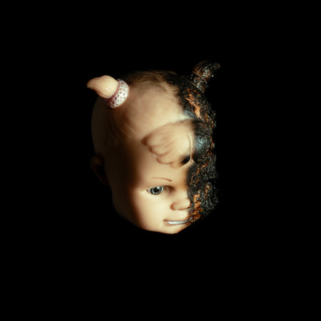 scary Isolated spooky possessed baby girl doll head creepy burnt face with gray eye on black background Close up macroの写真素材