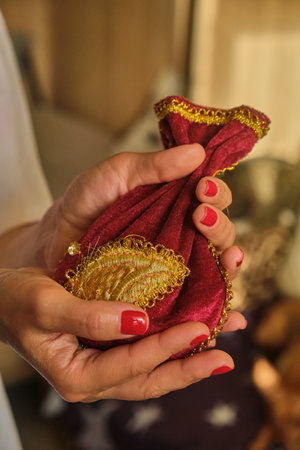 Womans Hands holding red esoteric bag with golden oriental pattern, taking tarot metaphoric cards deck out of occult pouchの写真素材