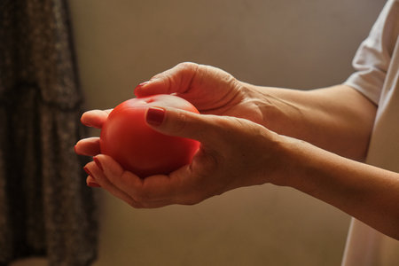 Close-up of a young woman's hand harvesting red juicy tomatoes. Picks a large tomato from a branch of a plant bush.の写真素材