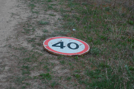 dirt road with 40 kmh speed limit and warning sign lies on the groundの写真素材