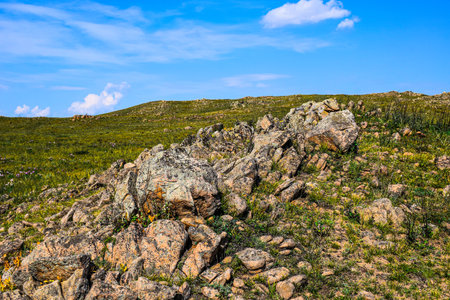 Mountain landscape with green grass and rocks on a background of blue sky. Khakassia, Siberia, Russia, Stone Park, Shirinsky Pillars, July Stone Parkの写真素材