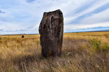 Ancient megalithic stone standing in the field of dry grass. Khakassia, Siberia, Russiaの写真素材