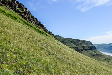 Landscape with green grass and mountains under blue sky with white clouds. Khakassia, Siberia, Russiaの写真素材