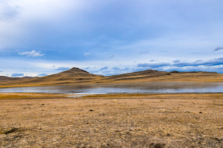 Dry grassland and lake under cloudy blue sky, Khakassia, Siberia, Russiaの写真素材