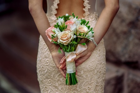 Beautiful bride with bouquet in hand, look from the backの写真素材